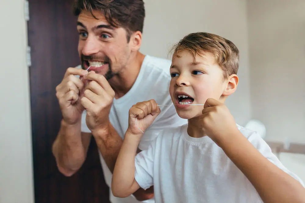 Son and father flossing their teeth